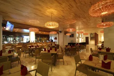 a restaurant with tables and chairs and chandeliers at Grand La Walon Hotel in Legian