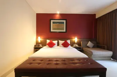 a bedroom with a large bed with red walls at Grand La Walon Hotel in Legian