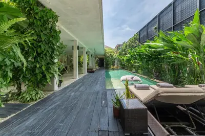 an outdoor swimming pool with a bathtub and a building at Villa Saba 10 in Seminyak