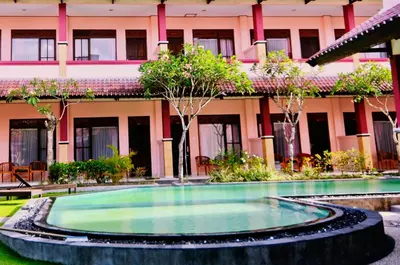 a swimming pool in front of a building at Pesona Beach Inn in Kuta