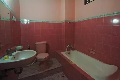 a bathroom with a toilet and a tub and a sink at Pesona Beach Inn in Kuta