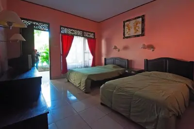 a hotel room with two beds and a window at Pesona Beach Inn in Kuta