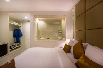 a bedroom with a large white bed and a bathroom at Amalfi Hotel Seminyak in Seminyak
