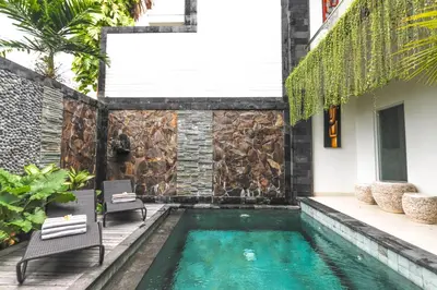 a swimming pool in the backyard of a house with two chairs at Puri Bagus Villa by Great Bali Villas in Legian