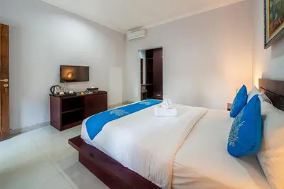 a bedroom with a large white bed with blue pillows at The Kutaya in Kuta
