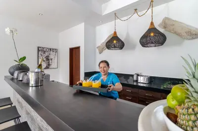 a man in a kitchen holding a tray of orange juice at Gorgeous Tropical 3 Bed Pool Villa, 24hr Security in Seminyak