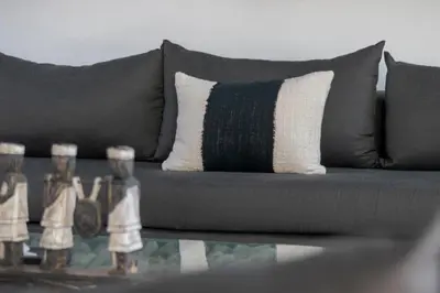 a gray couch with a pillow and two bottles on a table at Gorgeous Tropical 3 Bed Pool Villa, 24hr Security in Seminyak