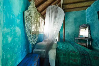 a bedroom with blue walls and a bed with a net at The Island Houses Seminyak in Seminyak