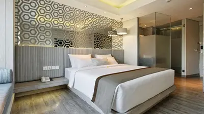 a bedroom with a large white bed and a couch at Hotel Daun Bali Seminyak in Seminyak