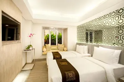a hotel room with two beds and a window at Hotel Daun Bali Seminyak in Seminyak