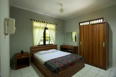 a bedroom with a large bed and a window at Sari Indah Cottages in Kuta
