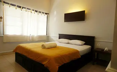 a bedroom with a bed with a yellow blanket at Sari Indah Cottages in Kuta