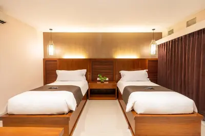 two beds in a hotel room with at Suka Beach Inn in Kuta