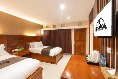 a hotel room with a bed and a television at Suka Beach Inn in Kuta