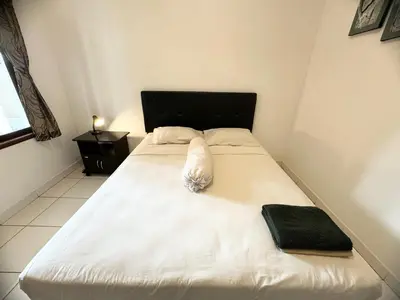 a bedroom with a white bed with a black headboard at Paradise Inn in Legian