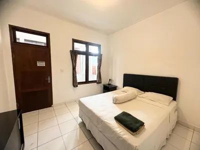 a bedroom with a bed with a black headboard and a window at Paradise Inn in Legian