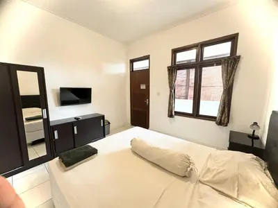 a bedroom with a large white bed and a window at Paradise Inn in Legian