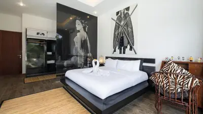 a bedroom with a large white bed and two chairs at NicoNico Mansion by Villa Finder in Seminyak