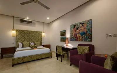 a bedroom with a bed and a couch and a table at The Residence Seminyak in Seminyak