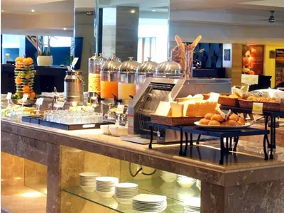 a breakfast buffet in a restaurant with bread and cheese at Aston Kuta Hotel and Residence in Kuta