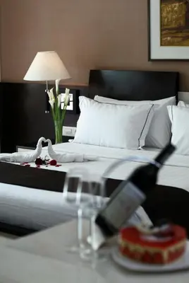 a hotel room with a bed and a table with a bottle of champagne at Aston Kuta Hotel and Residence in Kuta