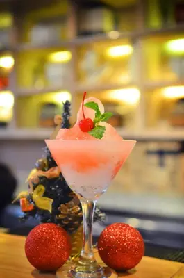 a drink in a glass with a strawberry on a table at Away Bali Legian Camakila in Legian