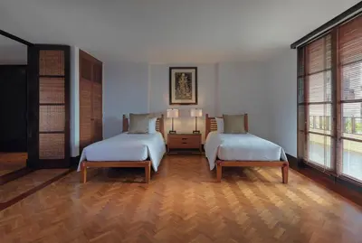 two beds in a room with two windows at The Legian Seminyak, Bali in Seminyak