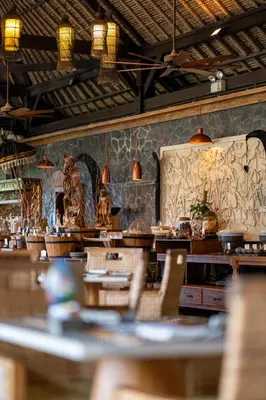 a restaurant with tables and chairs in a room at Jimbaran Puri, A Belmond Hotel, Bali in Jimbaran