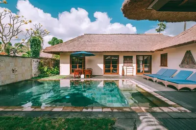 a villa with a swimming pool and a house at Jimbaran Puri, A Belmond Hotel, Bali in Jimbaran