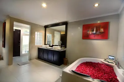 a bathroom with a large bath tub with a red rug at Bali Rich Villas in Seminyak