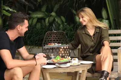 a man and woman sitting at a table with a plate of food at The Wolas Villas in Seminyak