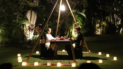 a man and woman sitting at a table with candles at The Wolas Villas in Seminyak