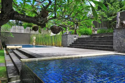 a swimming pool in a backyard with a tree and stairs at Abi Bali Resort and Villa in Jimbaran