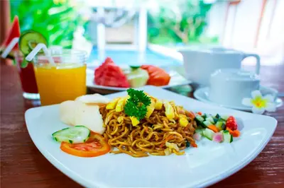 a plate of food with noodles and vegetables on a table at Abi Bali Resort and Villa in Jimbaran