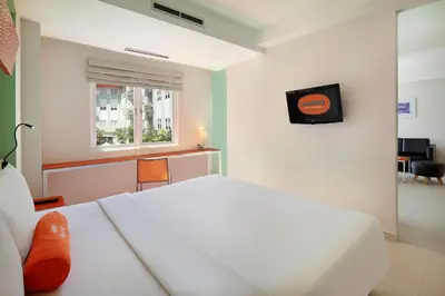 a bedroom with a white bed and a television at HARRIS Hotel & Residences Riverview Kuta, Bali in Kuta