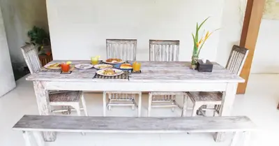 a wooden table with chairs and food on it at Villa Kim Seminyak in Seminyak