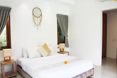 a white bedroom with two beds and a window at Villa Kim Seminyak in Seminyak