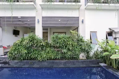a house with a swimming pool in front of a building at RedDoorz at Benesari 2 Legian in Kuta