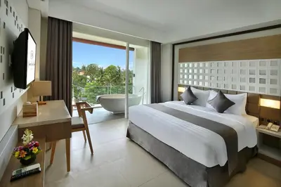 a bedroom with a bed and a bathroom with a tub at Jimbaran Bay Beach Resort and Spa by Prabhu in Jimbaran