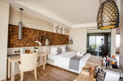 a bedroom with a large bed and a desk and a table at Jimbaran Bay Beach Resort and Spa by Prabhu in Jimbaran