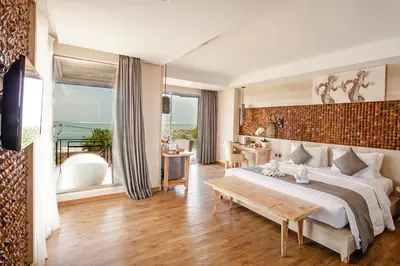 a bedroom with a large bed and a table at Jimbaran Bay Beach Resort and Spa by Prabhu in Jimbaran