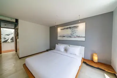 a bedroom with a white bed and a painting on the wall at Villa Rio - Contemporary 2BR Villa in Downtown Seminyak in Seminyak