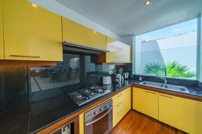 a kitchen with yellow cabinets and a large window at Villa Rio - Contemporary 2BR Villa in Downtown Seminyak in Seminyak