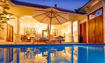 a house with a swimming pool with an umbrella at Villa Soleh in Seminyak