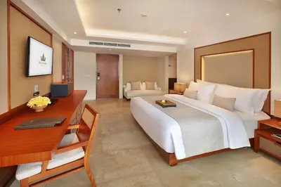 a hotel room with a large bed and a desk at The Bandha Hotel & Suites in Legian