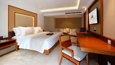 a hotel room with a large bed and a desk at The Bandha Hotel & Suites in Legian