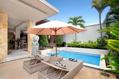 a pool with an umbrella and two chairs and a table with an umbrella at Villa J Deluxe in Canggu