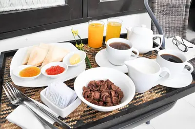 a tray with cups of coffee and breakfast foods at Paisa Villa Seminyak in Seminyak