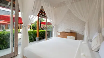a bedroom with a white bed and large windows at Villa Taramille by Villa Finder in Kerobokan