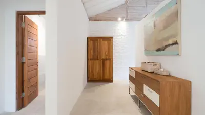 a hallway with a wooden dresser and a door at Villa Taramille by Villa Finder in Kerobokan